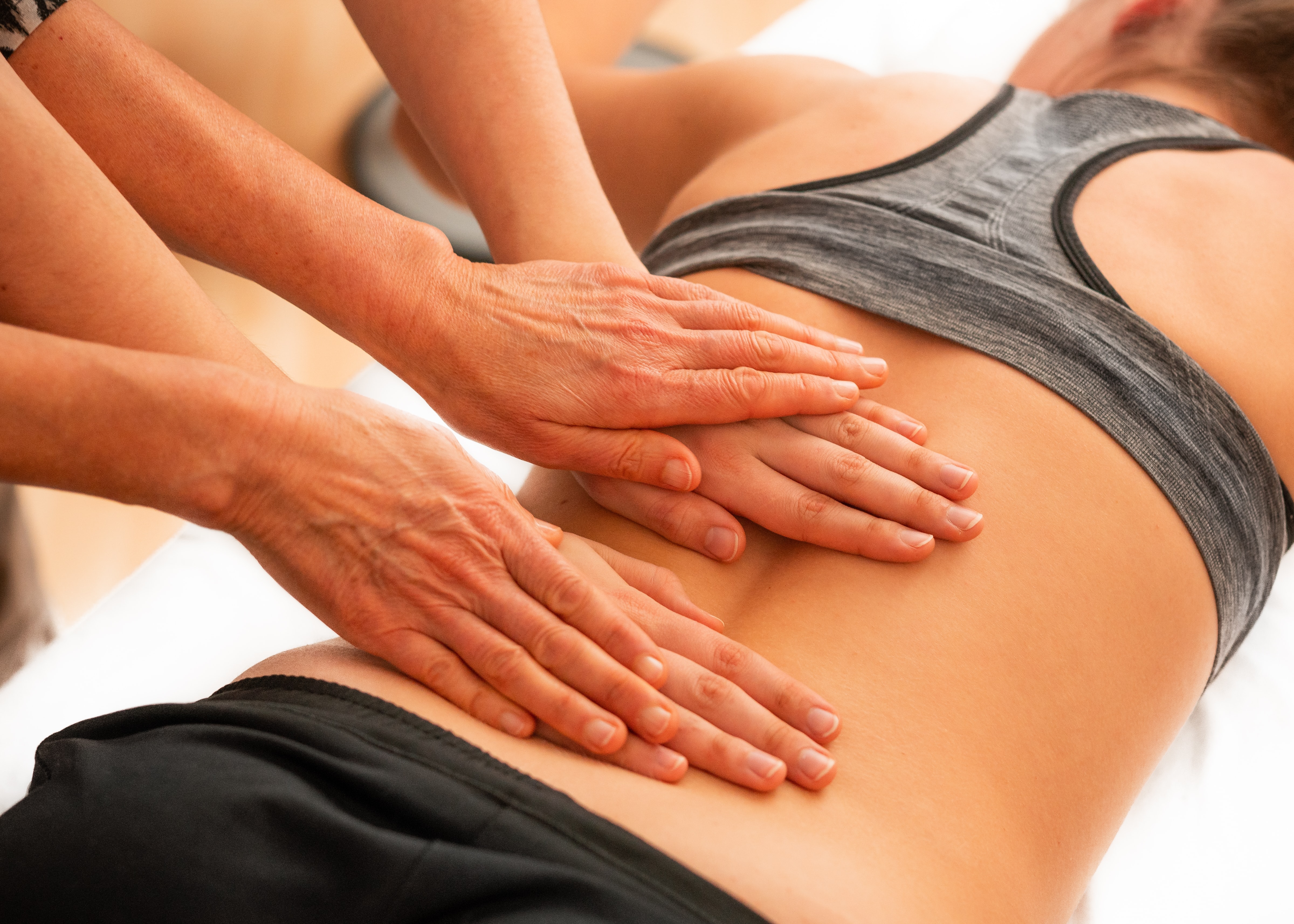 tipologie mal di schiena - 4 mani che massaggiano una schiena femminile