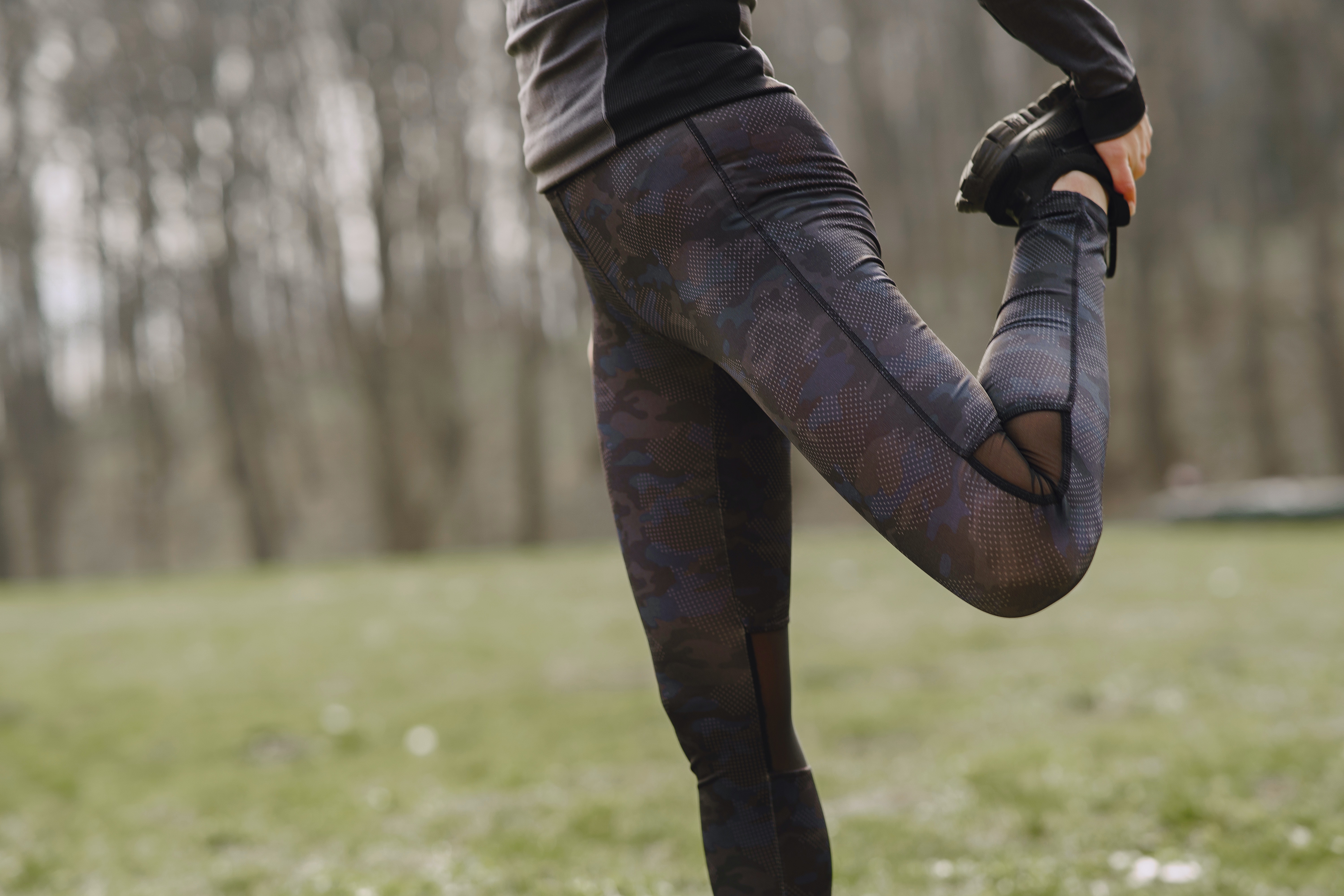 stiramento muscolare cause e rimedi - donna vestita da running che fa stretching per allungare i muscoli della coscia